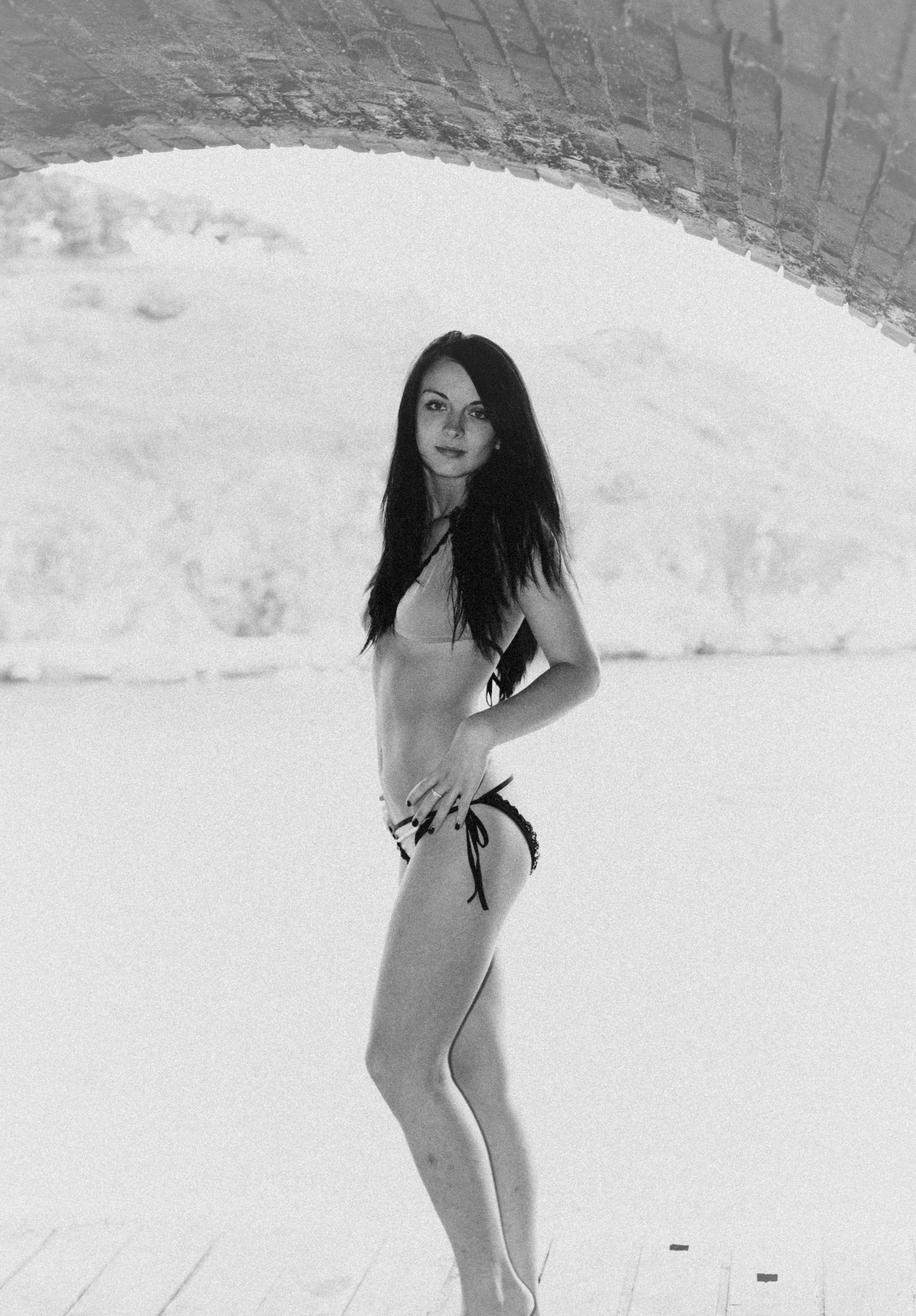 Monochrome swimsuit portrait beneath a stone arch